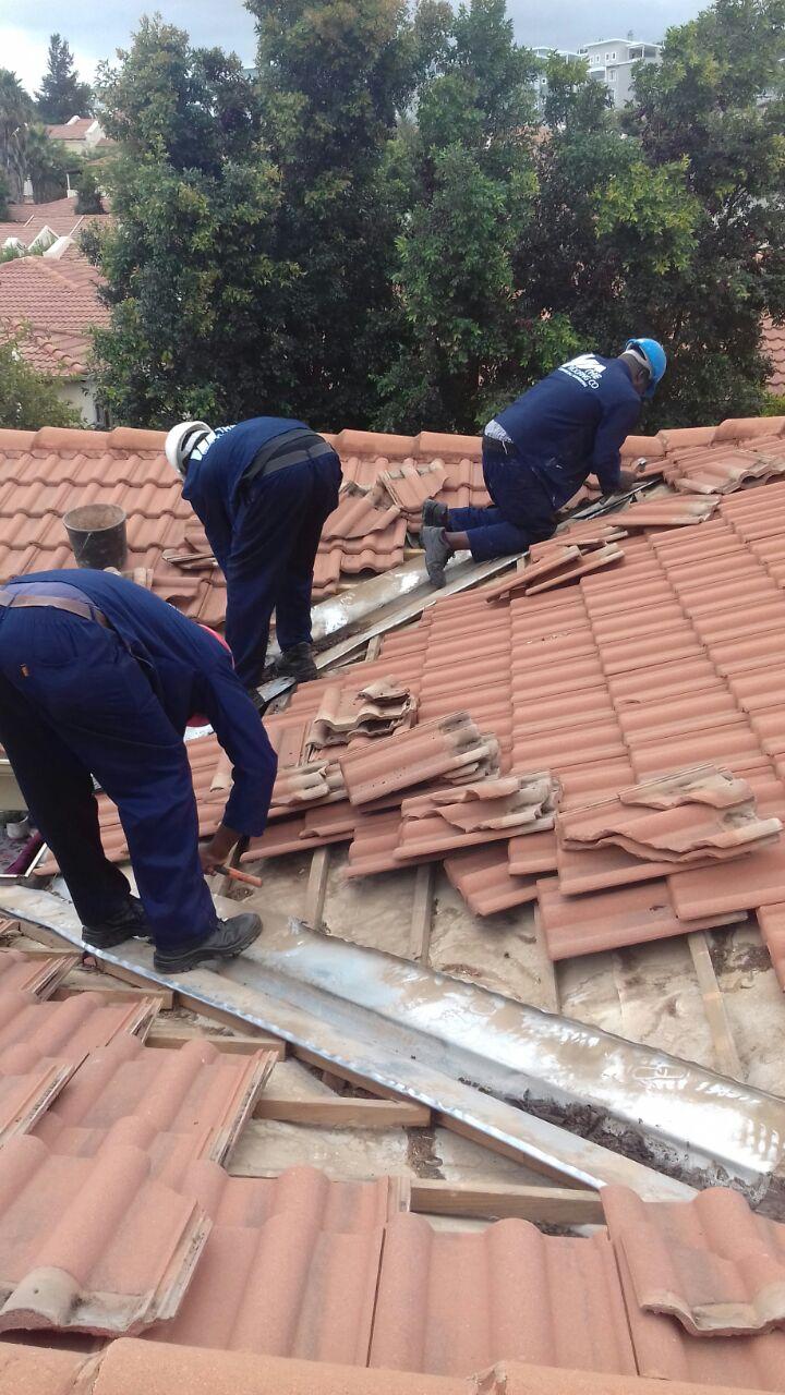 Roofing team repairing roof tiles