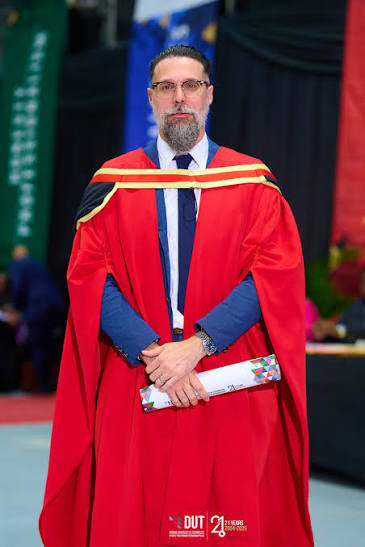 Academic in red gown holding certificate